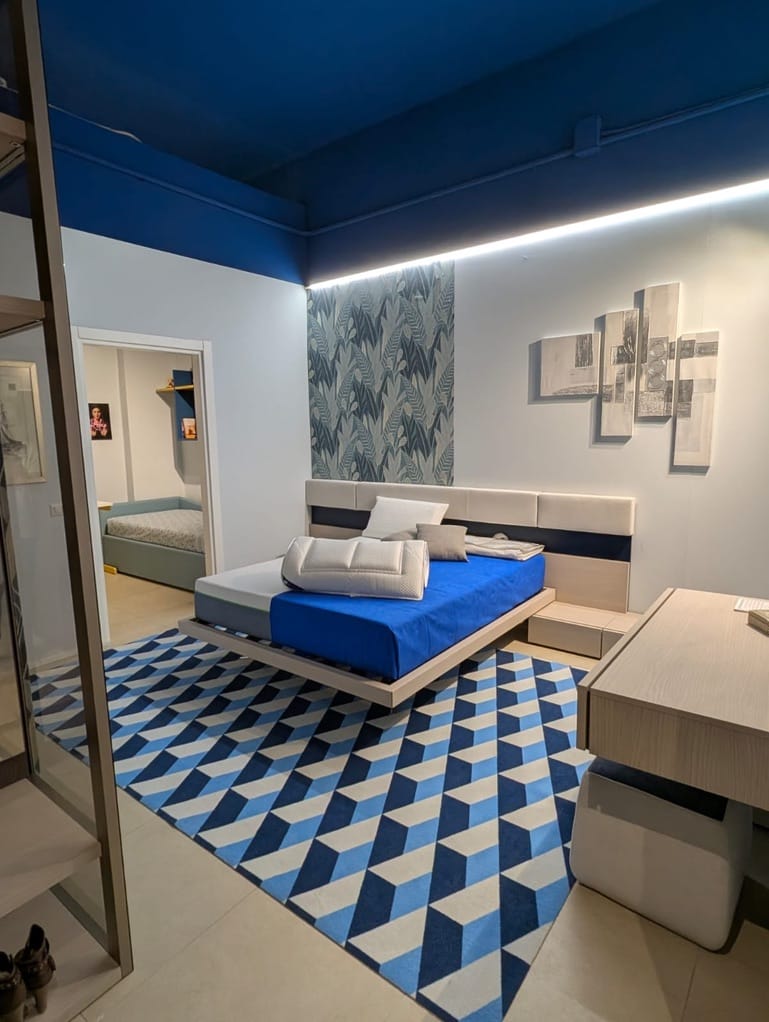 Camera da letto con tappeto a cubi blu e bianchi ai piedi del letto